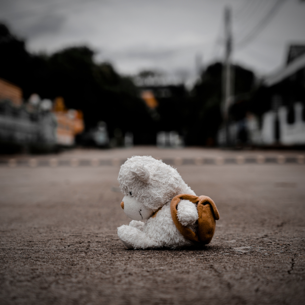 a teddy bear sitting on the ground in the middle of an empty street